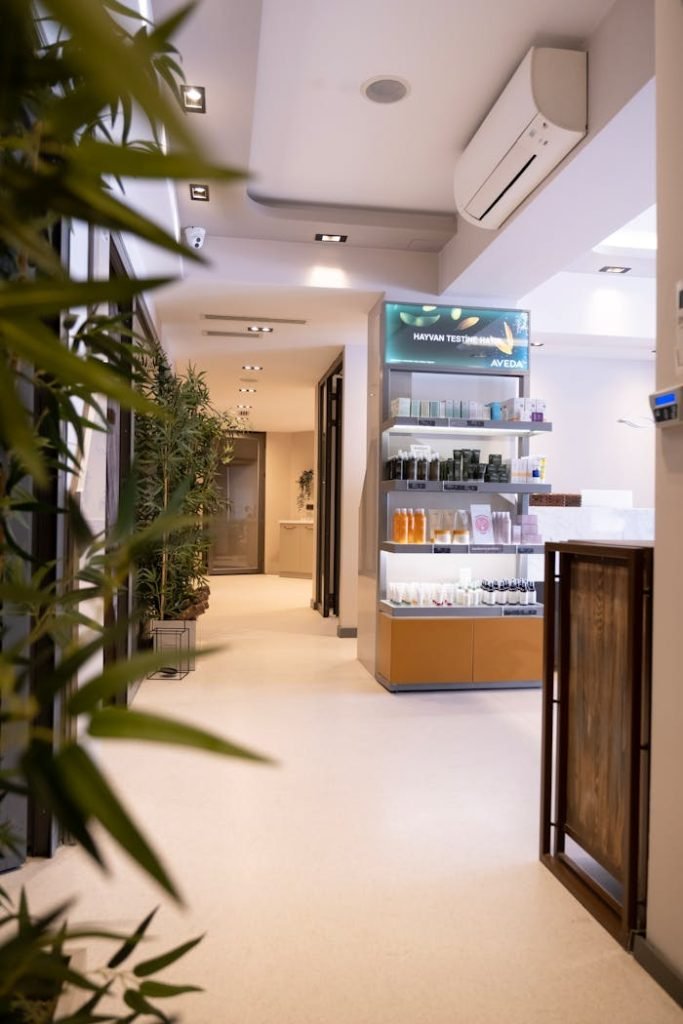 Elegant spa corridor featuring a product display and potted plants under soft lighting.